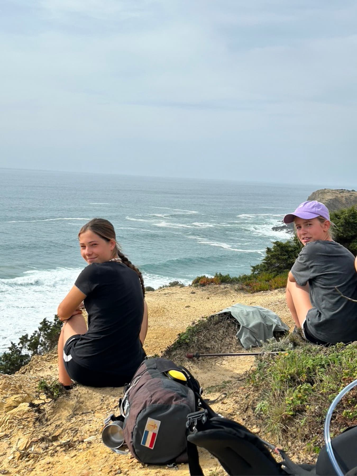 A hiker resting on a cliff looking out over the ocean